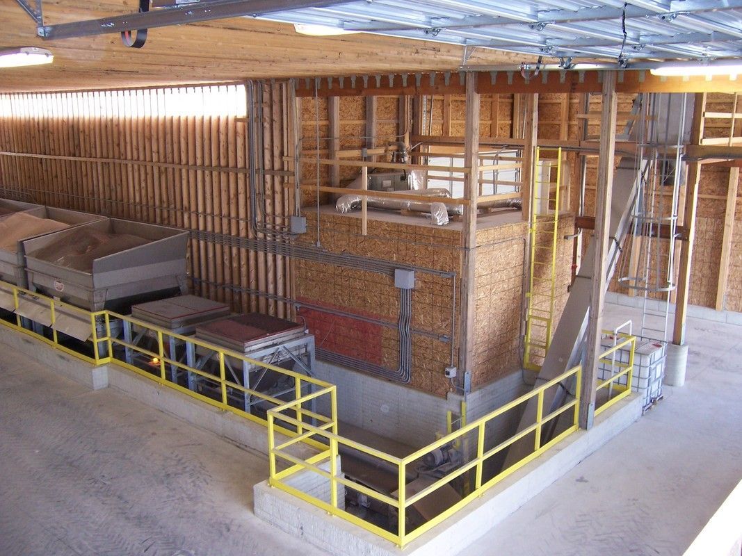 Industrial interior with yellow safety railings around brick machinery and wooden framing.