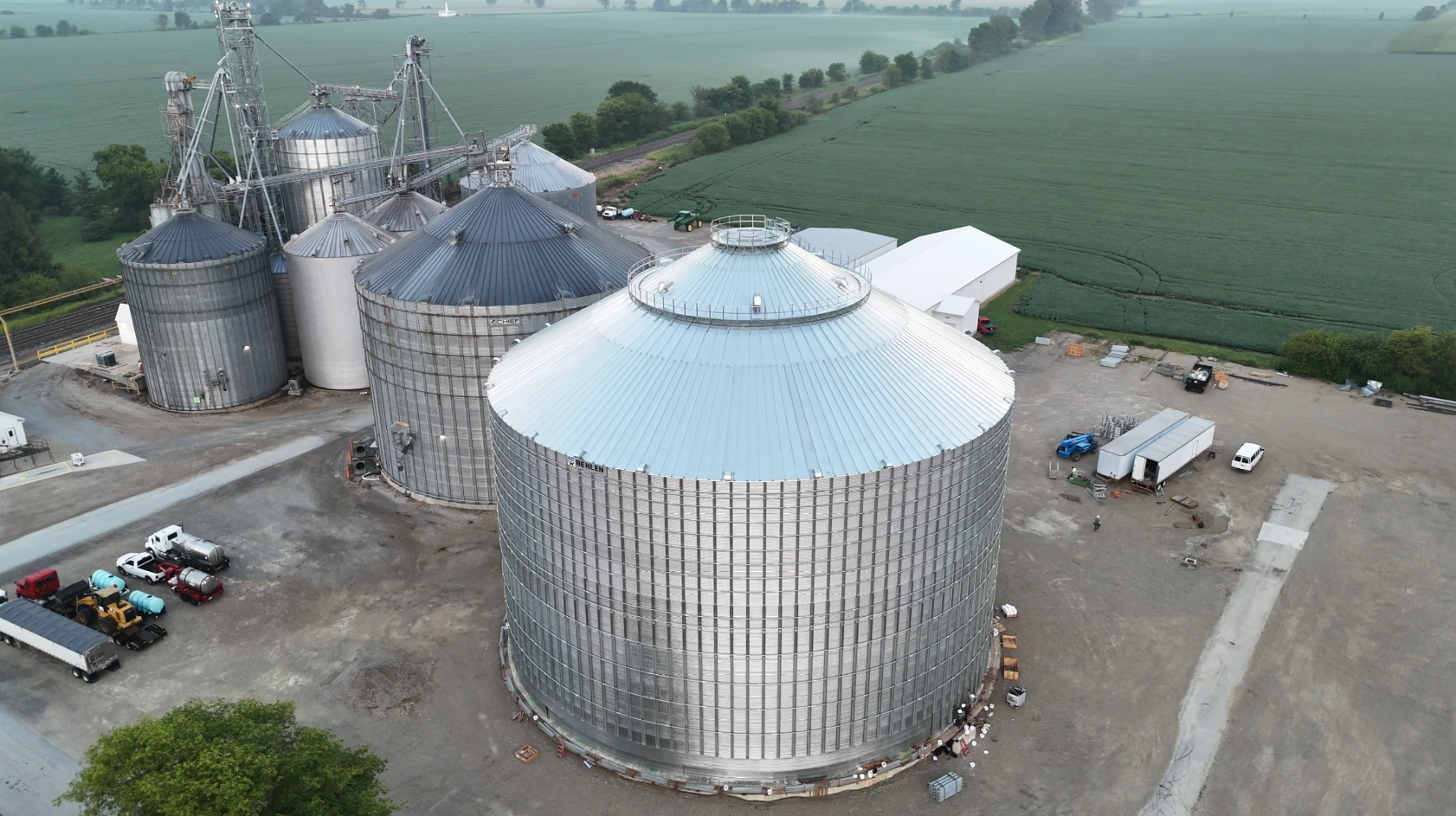 Aerial view of large metal grain silos and storage bins beside farm fields