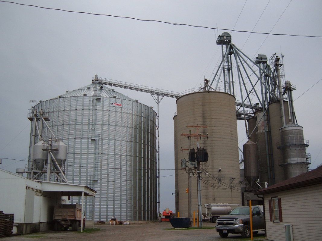 Grain silos and industrial storage tanks at a farm facility under a gray sky