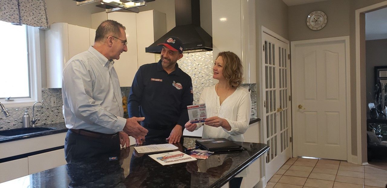Three people talking in a kitchen, with papers on a countertop.
