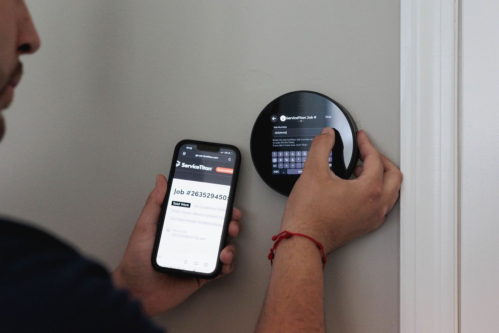 Person using a phone to view a smart home control panel mounted on a wall