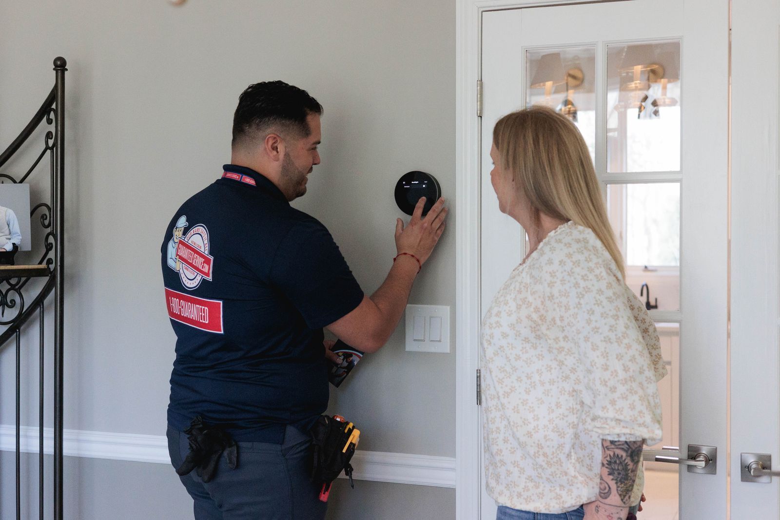 Police officer showing a device on a wall to a woman in a hallway