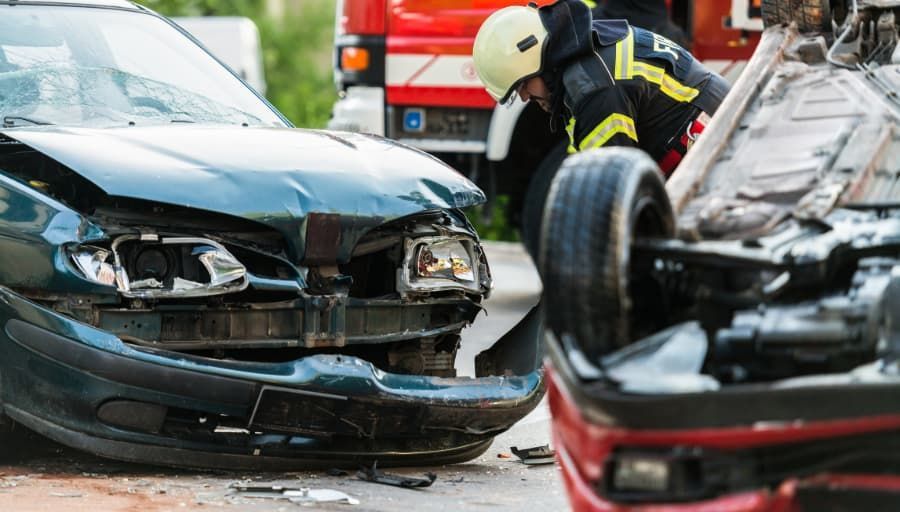Firefighter at scene of accident with two badly wrecked cars Firefighter at scene of accident with two badly wrecked cars
