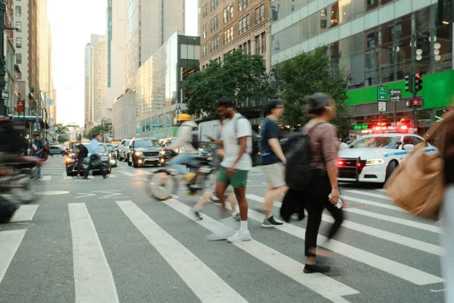 Wrecked bicycle, helmet, and eyeglasses on road in front of white car Pedestrians in crosswalk in New York.