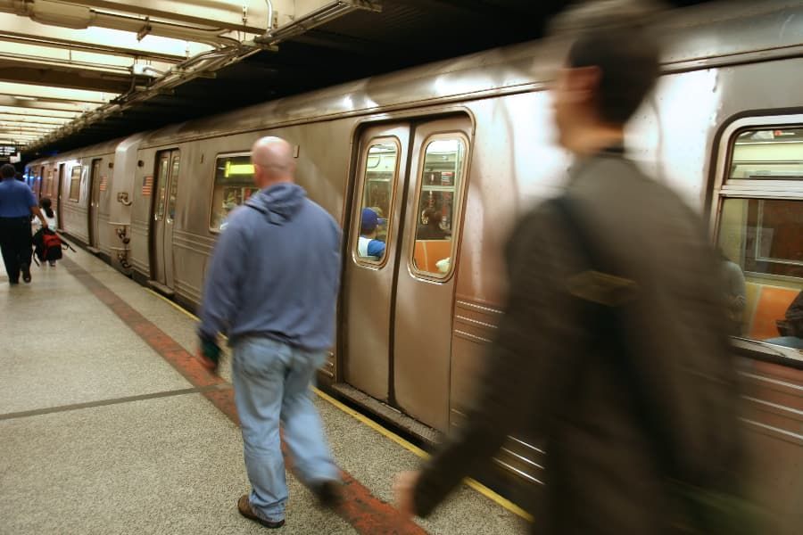 Blurred image of subway train and two men walking on platform.