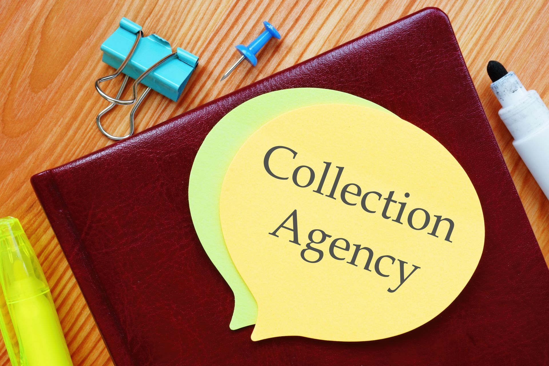 Notebook with a sticky note labeled collection agency resting on a desk with office supplies. Notebook with a sticky note labeled collection agency resting on a desk with office supplies.