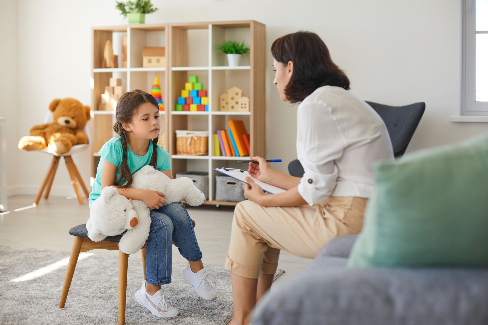 Little girl sharing her concerns with supportive child psychologist during therapy session.