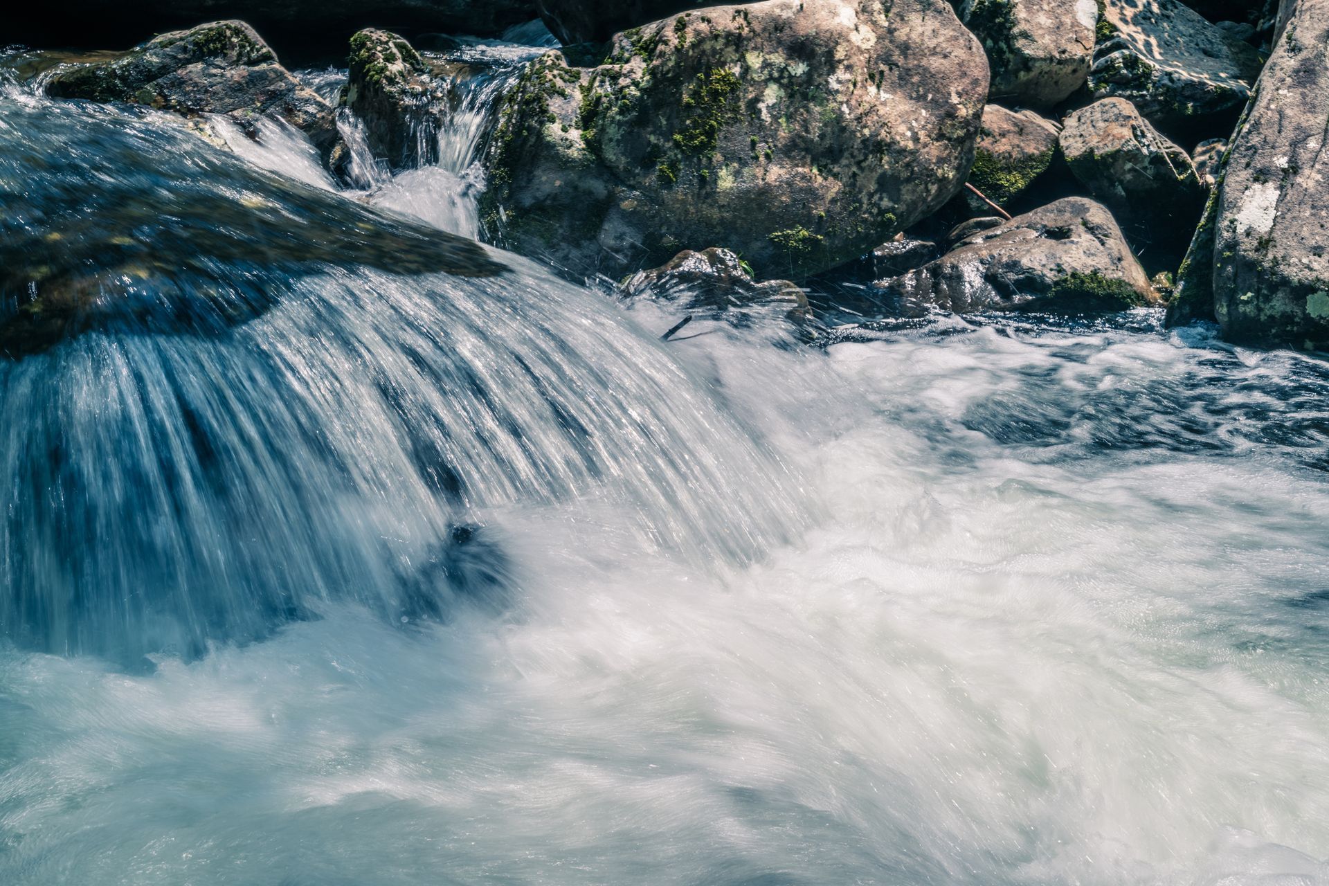 Flowing stream cascading over rocks into white water in a natural setting