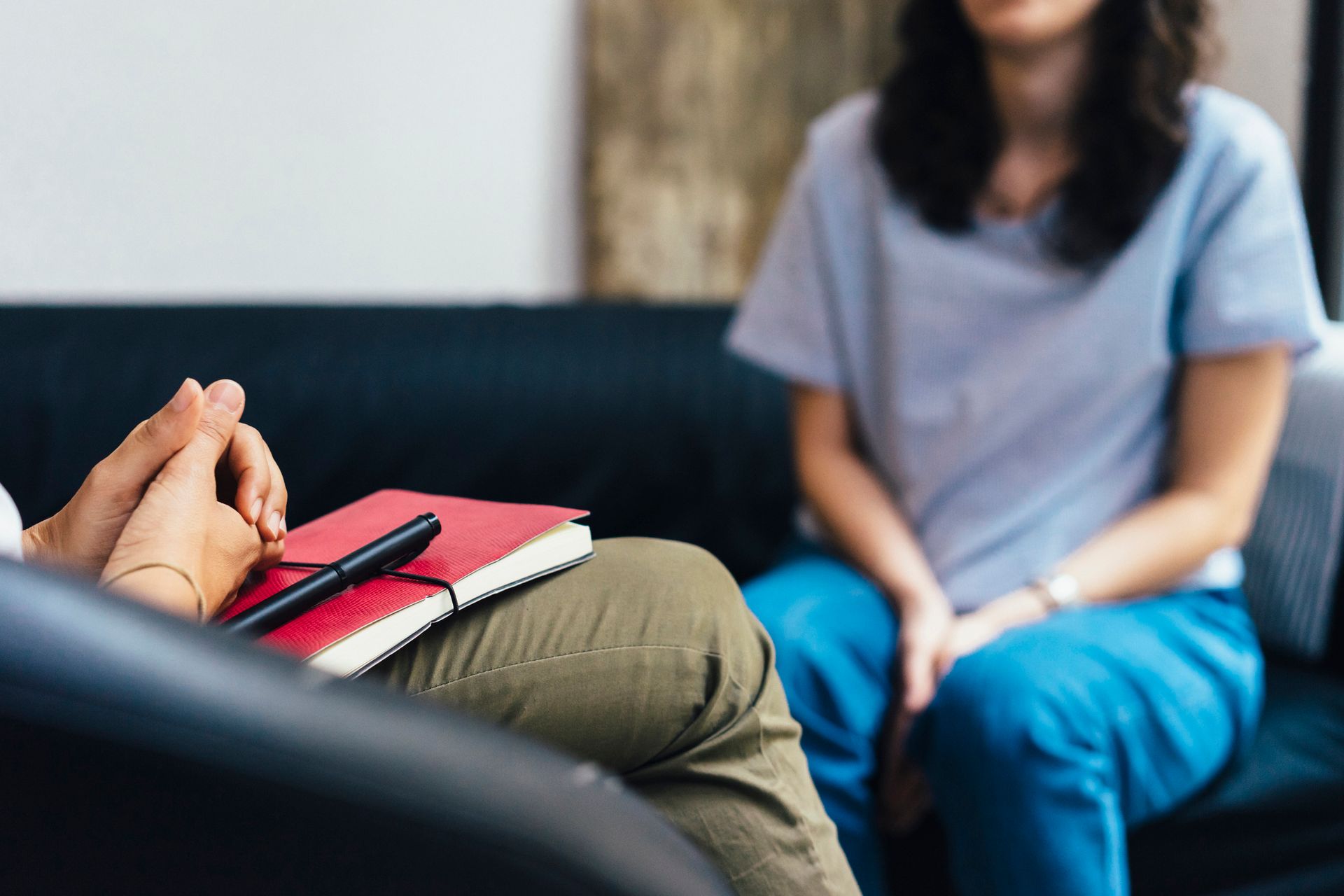 Psychotherapy Session — Stow, OH — Western Reserve Psychological Associates, Inc. Two people talking in a living room, with a notebook in the foreground.