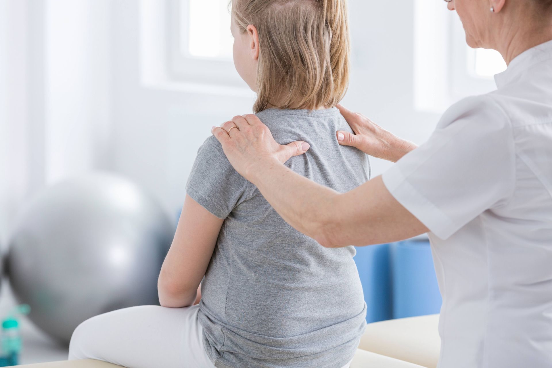 Parent learning about childhood scoliosis while a chiropractor explains spinal development