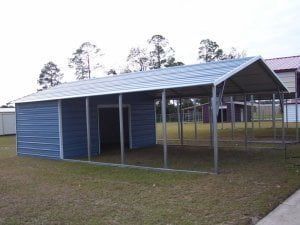 A blue metal shed with a roof is sitting in the grass.