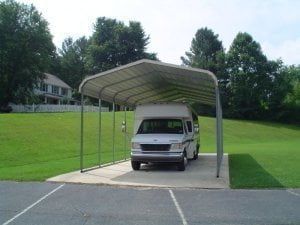 A white van is parked under a carport in a parking lot.