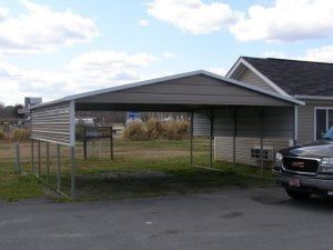 A car is parked under a carport in front of a house.