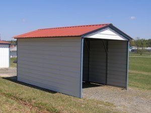 A small metal shed with a red roof is sitting in the middle of a grassy field.