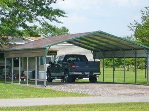 A truck is parked under a carport in front of a house.