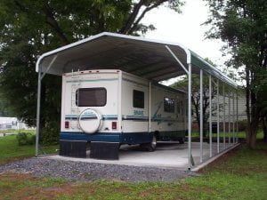 A rv is parked under a carport.