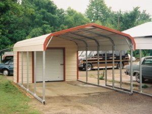 A car is parked under a carport next to a garage.