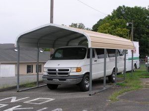 A white van is parked under a carport.