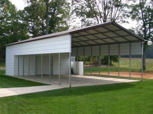 A white metal garage with a brown roof is sitting on top of a lush green field.