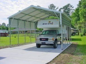 A truck is parked under a canopy in a driveway.