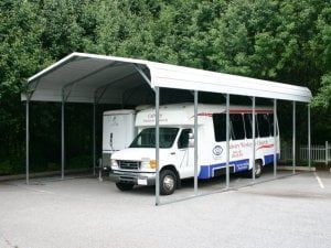A white bus is parked under a white canopy.