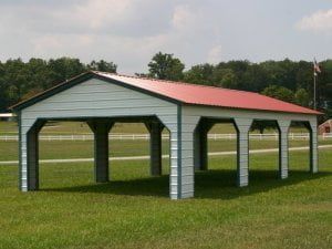 A white carport with a red roof is sitting in the middle of a grassy field.