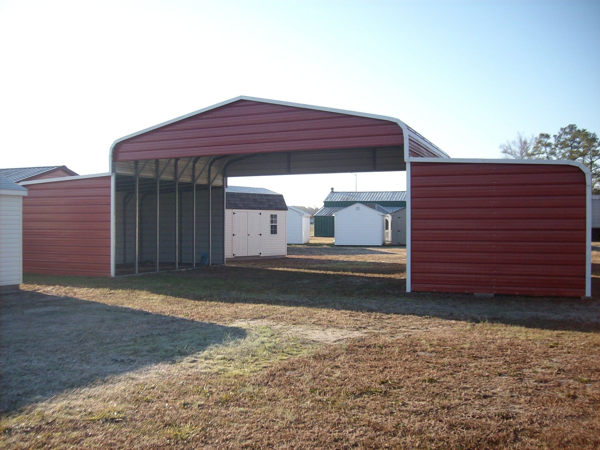 A red barn is sitting in the middle of a dirt field.