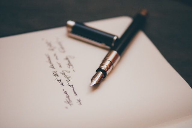 Fountain pen resting on a handwritten letter on white paper