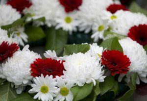 Red and white flowers with green leaves arranged in a bouquet
