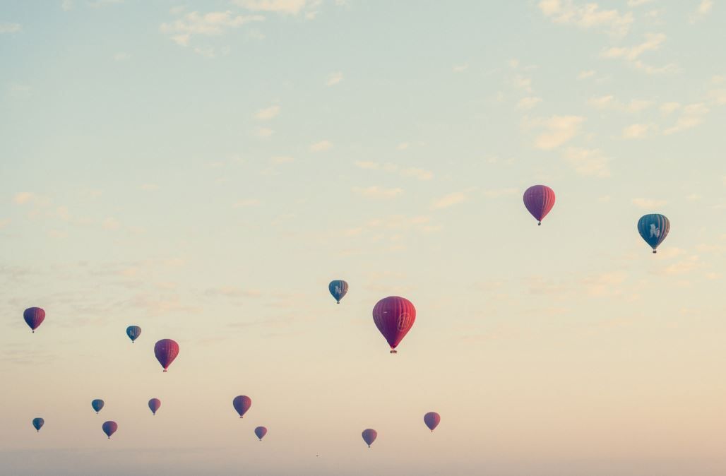 Hot air balloons floating in a pastel sunset sky
