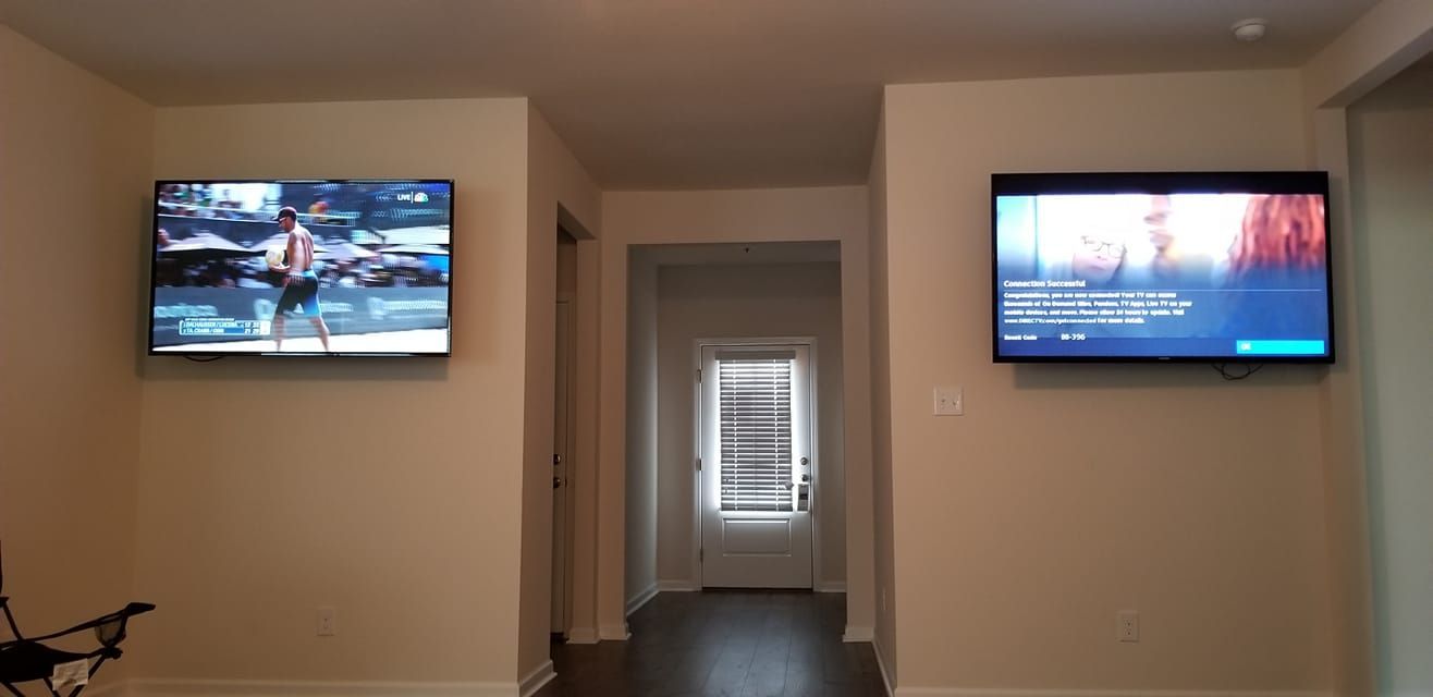 Two flat screen tvs are hanging on the wall in a hallway.