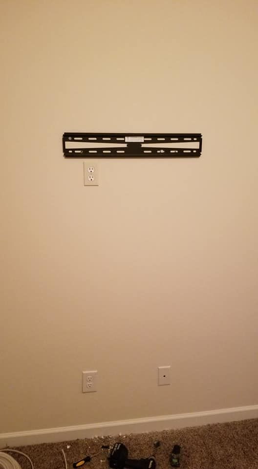 A tv mount is hanging on a wall in a living room.