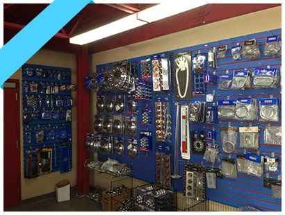 Allée d'une quincaillerie avec des panneaux perforés bleus présentant des outils et des pièces emballés