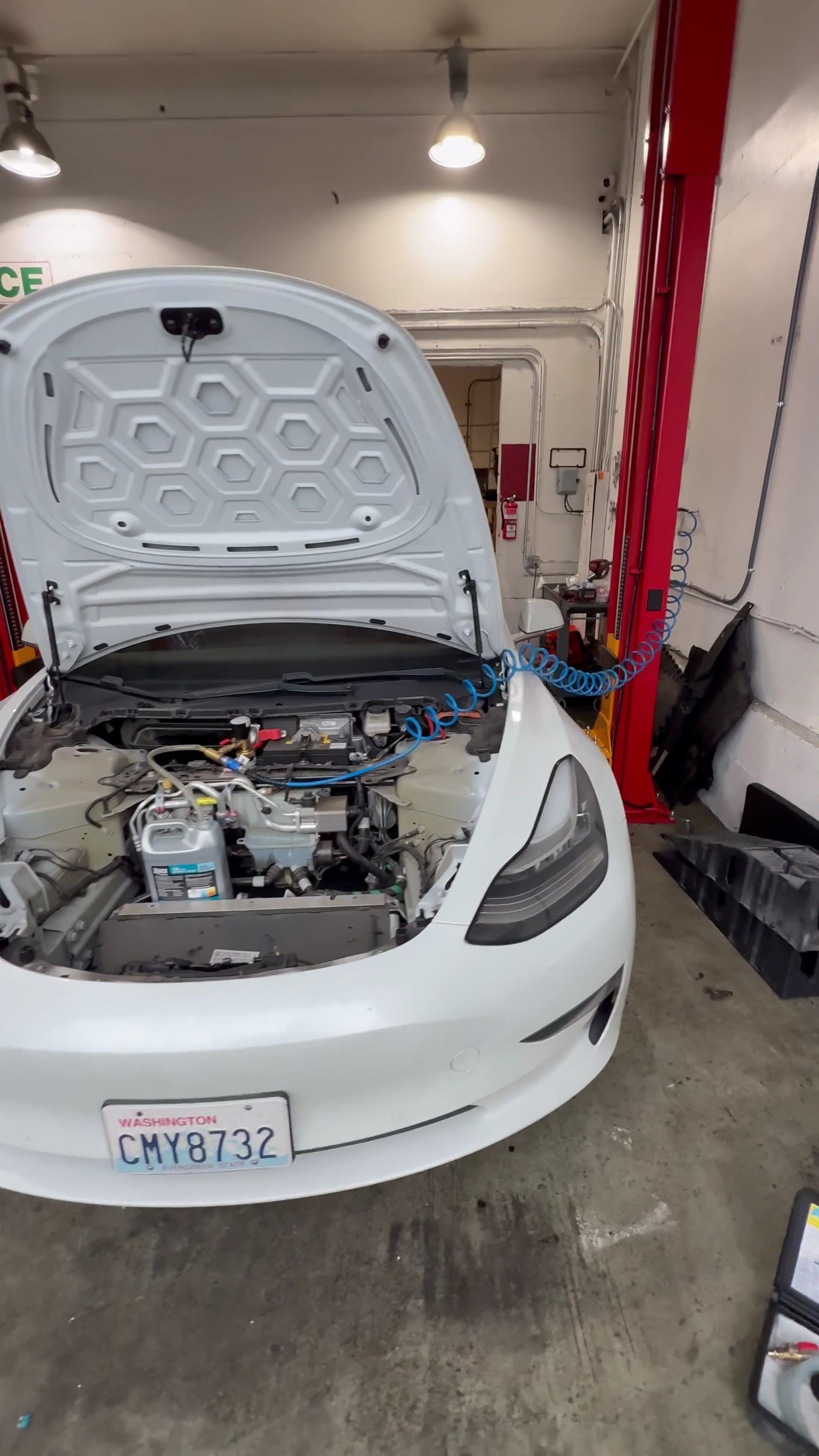 White car in a garage with the hood open, showing the engine bay and a red tool cart nearby. | Lapin Auto Repair
