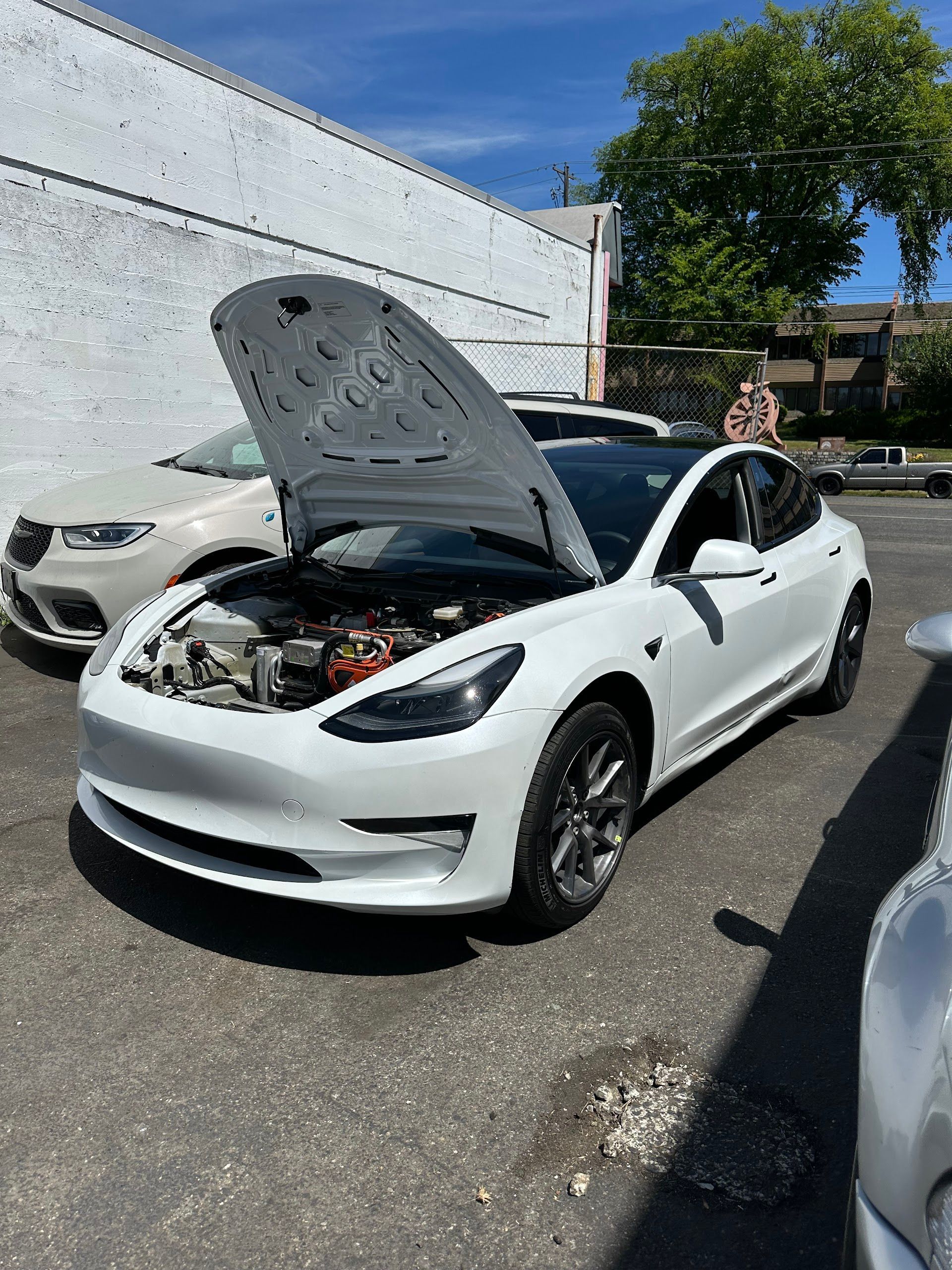 White Tesla with hood open in a parking lot, exposing the engine compartment. | Lapin Auto Repair