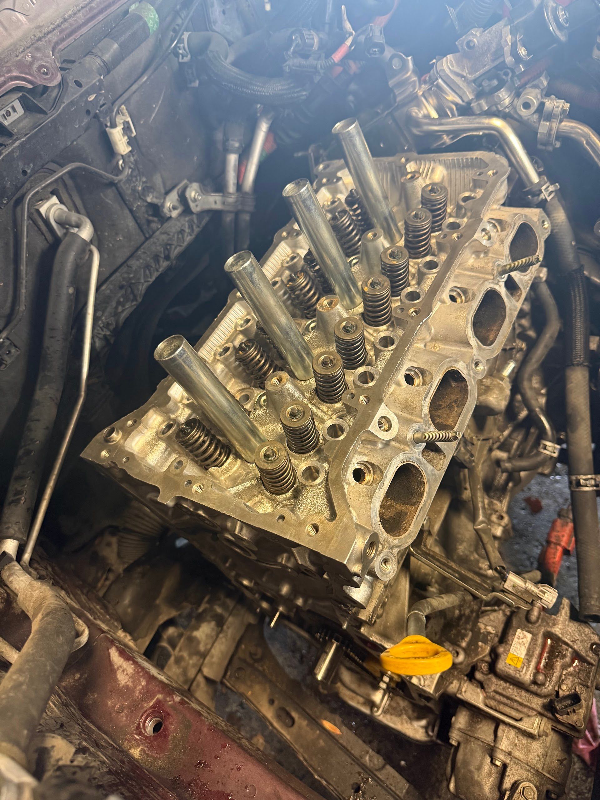Engine block in a dirty car bay, with pistons and components exposed during repair. | Lapin Auto Repair