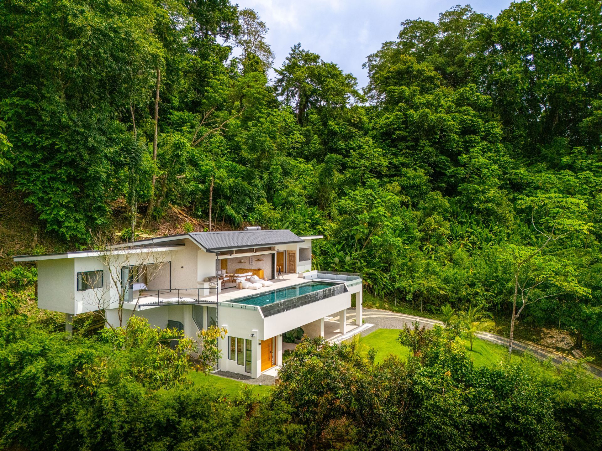 Modern white house with balcony nestled in lush green forest hillside