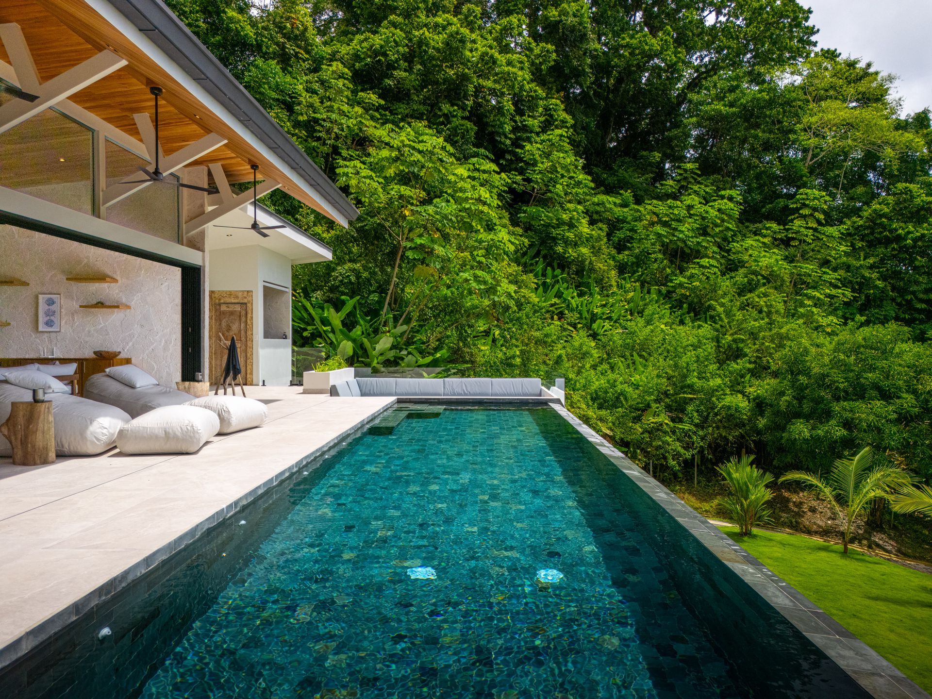 Modern villa terrace with an infinity pool overlooking lush green hillside