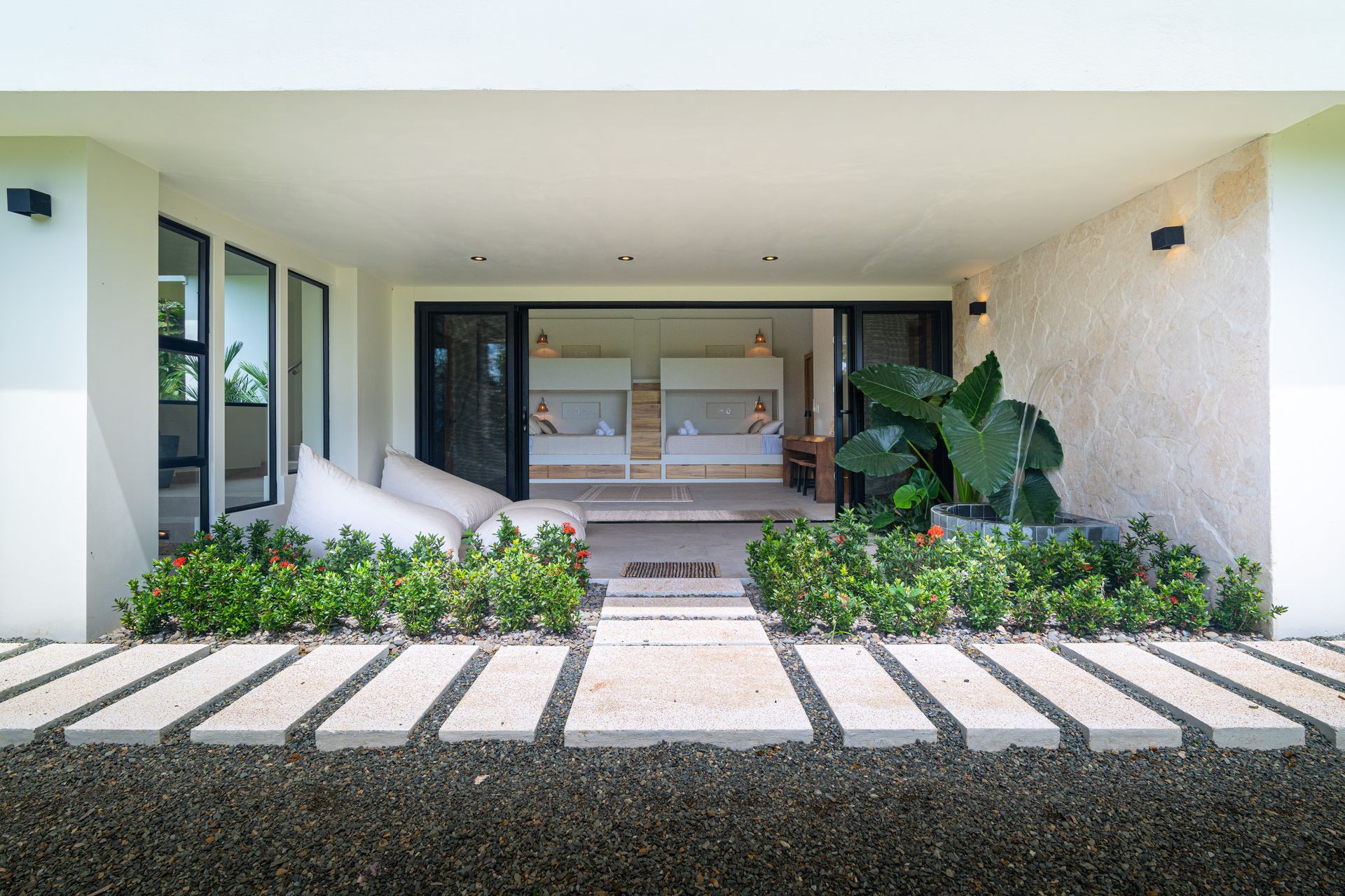 Modern front porch with white stepping stones, potted plants, and a wide open doorway