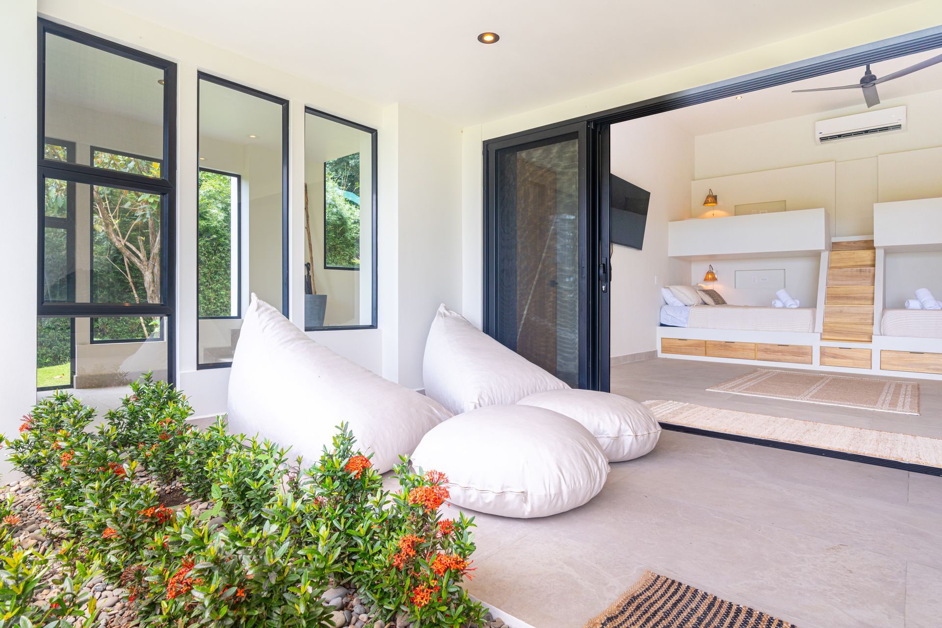 Modern patio with white beanbags, black-framed windows, and an open view into a bright bedroom.