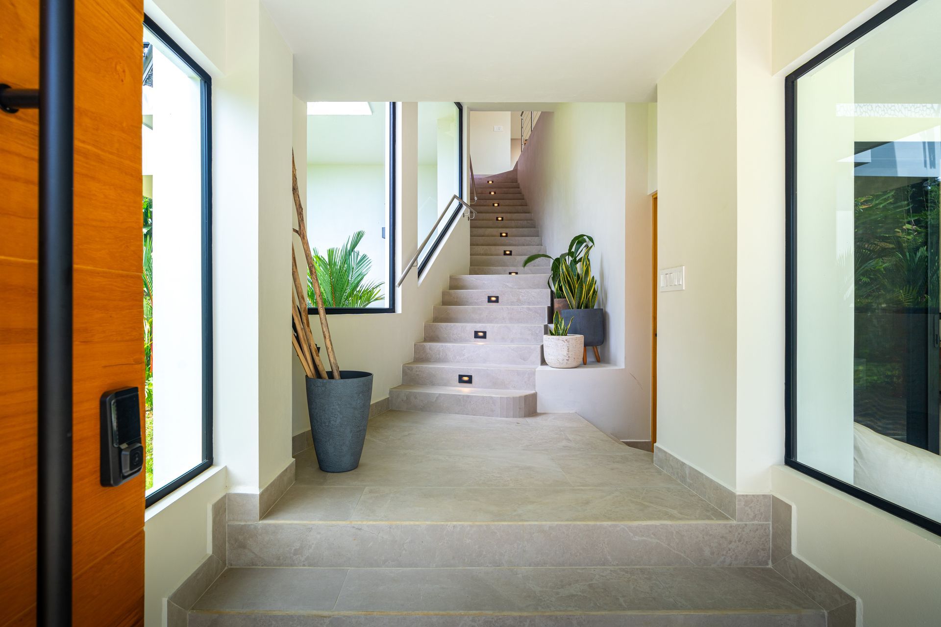 Modern entryway with staircase, large windows, and potted plants