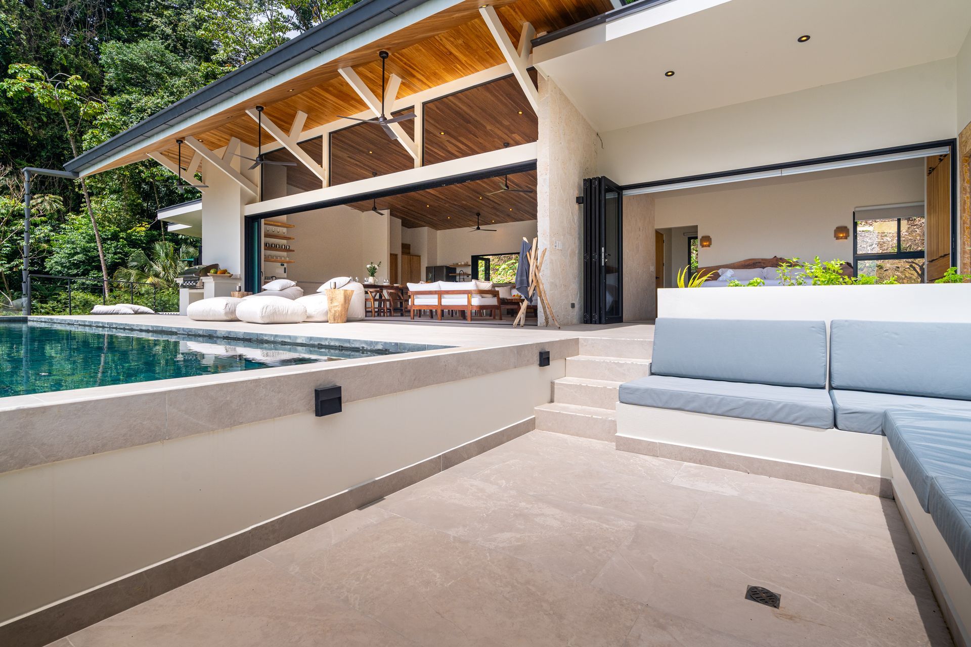 Modern patio with a pool, steps, and a covered outdoor lounge beside a house