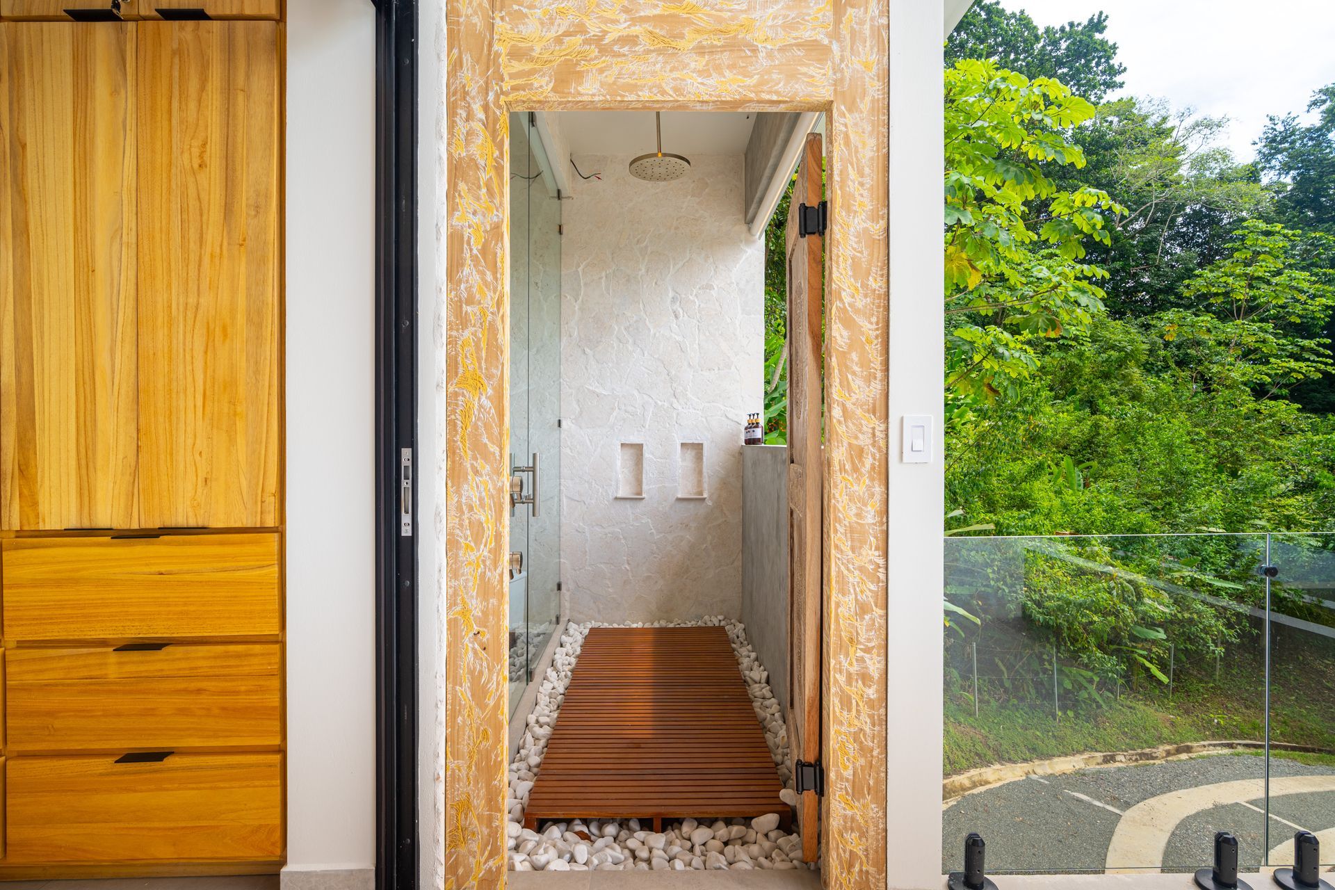 Modern doorway with wood cabinet on left and a narrow hall opening to a green garden outside