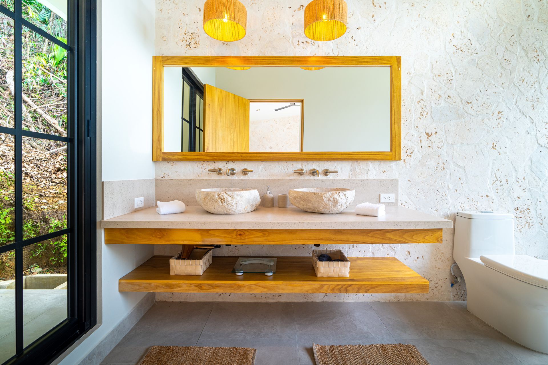 Modern bathroom vanity with stone sink, wood shelves, and large gold-framed mirror