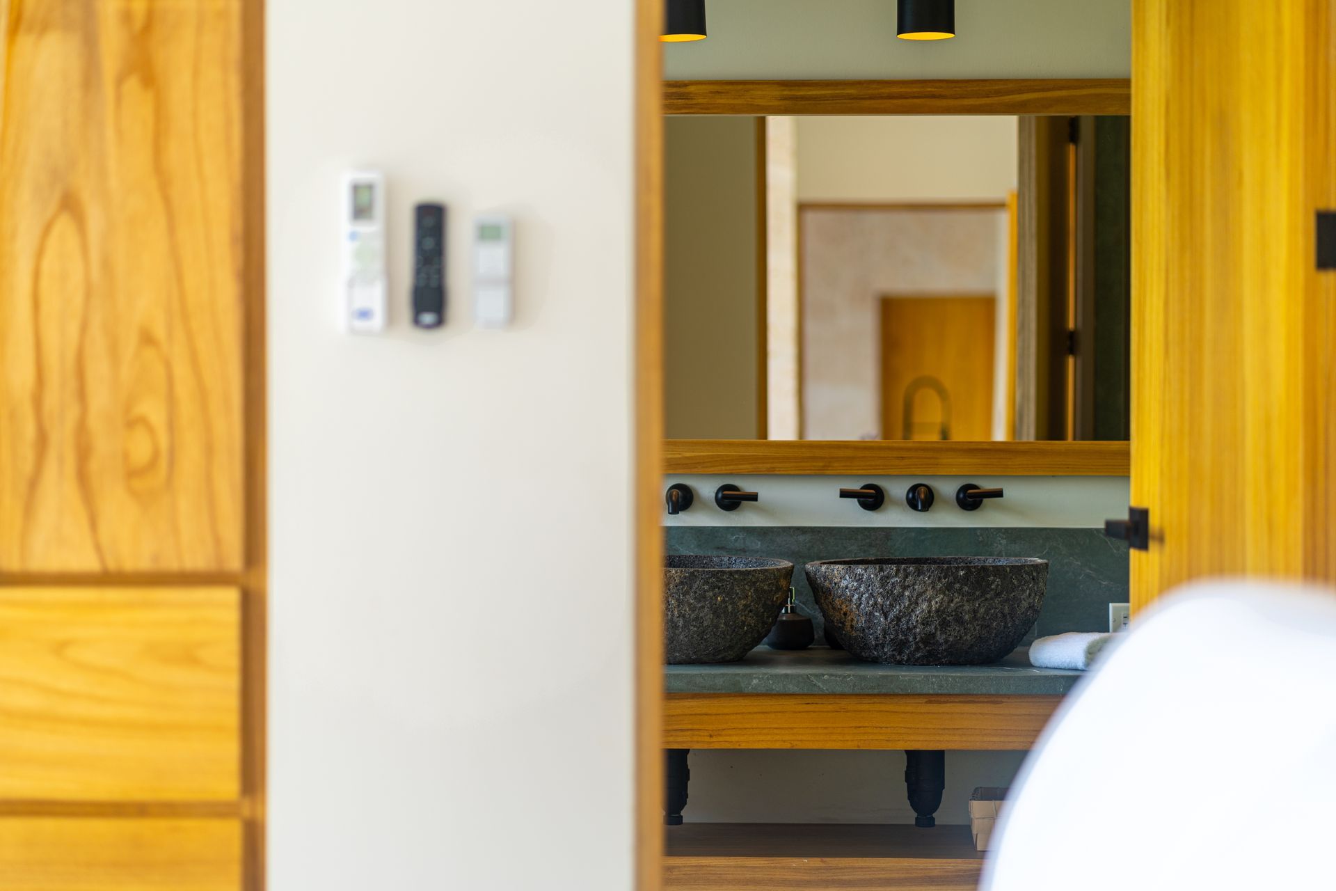 Modern interior with wooden furniture, mirror, sink, and wall-mounted control panel