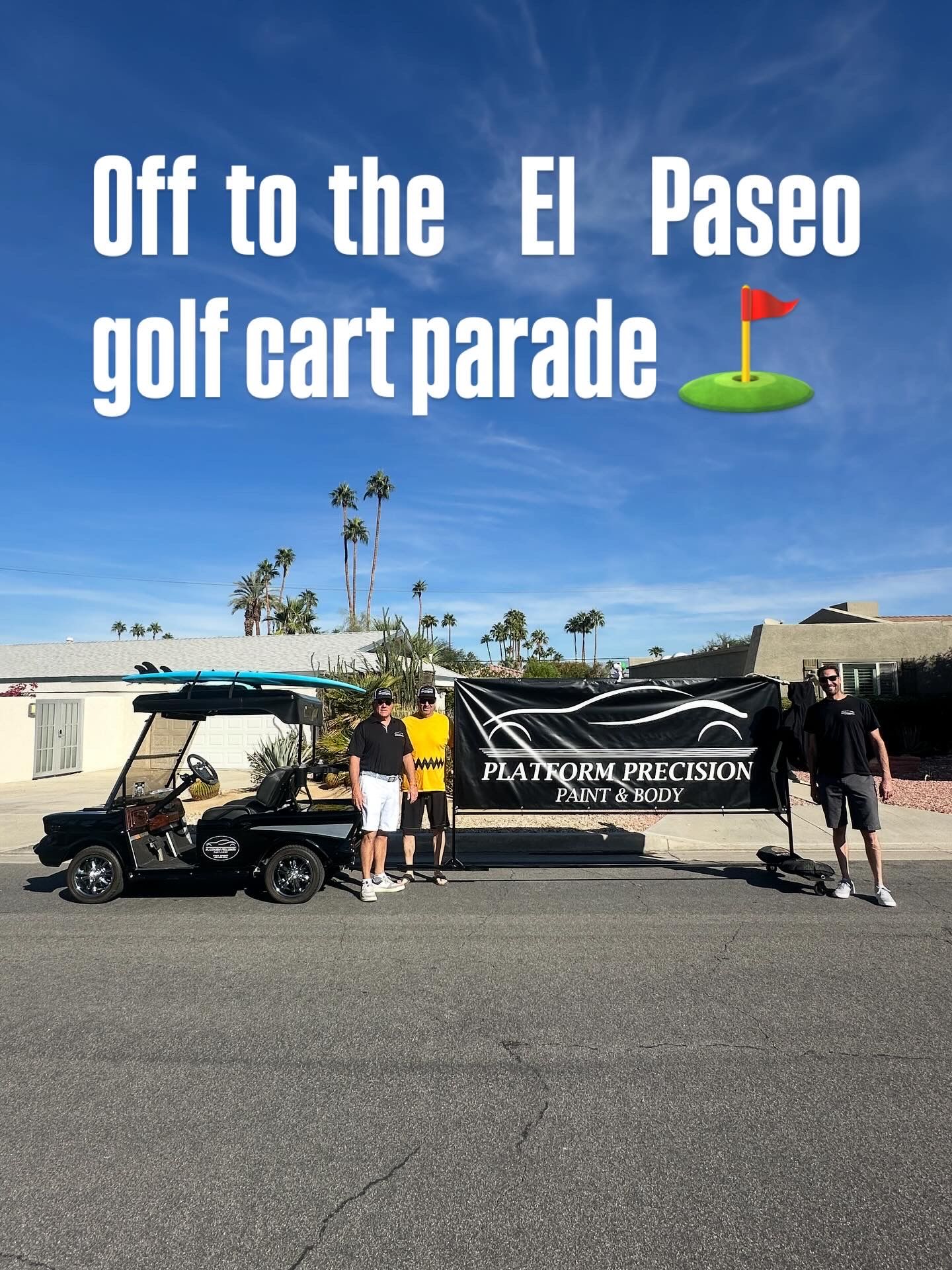 Golf cart parade with three people standing with a banner. Blue sky, sunny day.