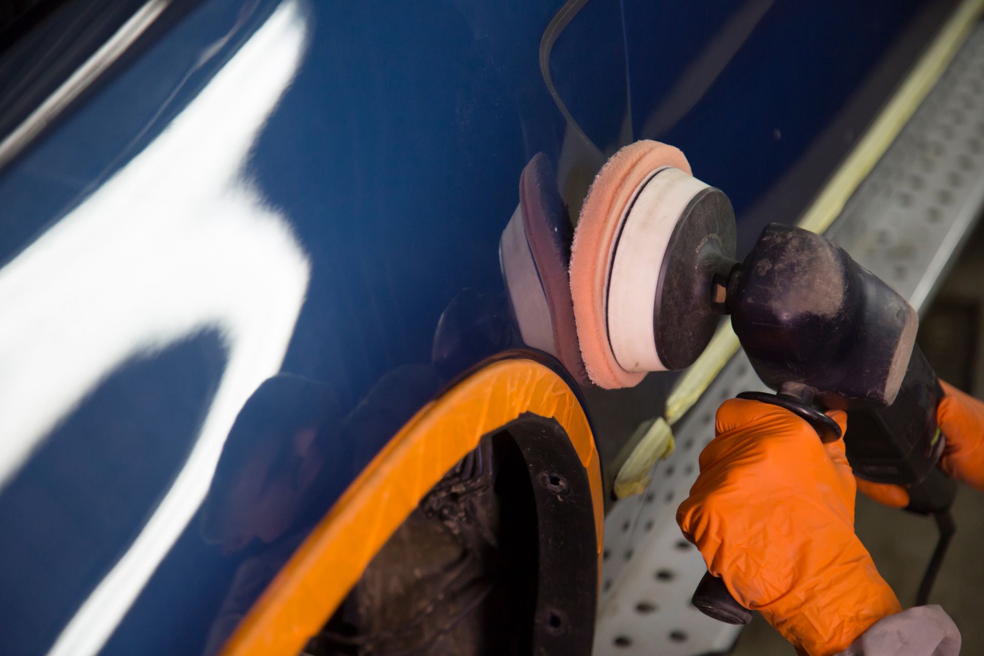 Auto body worker polishing a car door with an electric buffer. Auto body worker polishing a car door with an electric buffer.
