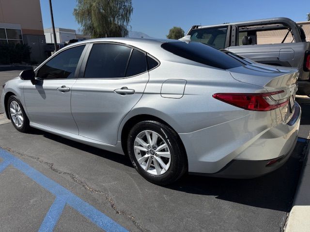 Silver sedan parked in a parking lot, tinted windows, sunny day.