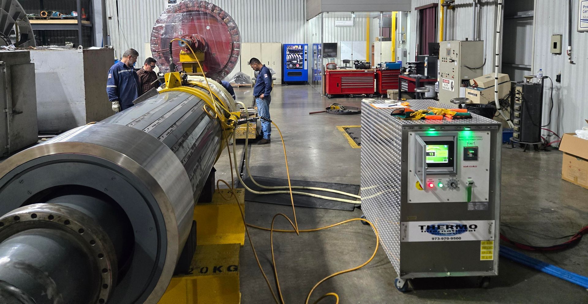 Des ouvriers près d'équipements industriels, probablement en train de tester ou de réparer, dans une usine.