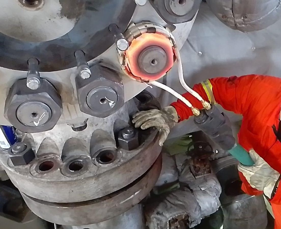 Une personne portant un équipement de protection orange utilise un outil sur une machine industrielle